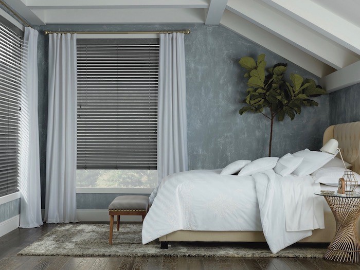 A well organized bedroom with bench and lots of pillows.